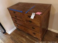 Front view of wood hutch with six drawers, showing scratches and blue tape sealing the top.