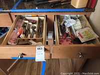 Two drawers open containing various kitchen utensils in plastic trays and loose items.
