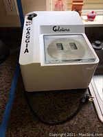 Full view of white Gaggia Gelatiera gelato maker on countertop showing housing, lid, power cord and plug