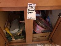 Photo showing two wooden cabinets filled with assorted personal care bottles, containers, and boxes, including a yellow lotion bottle, blue plastic case, pink basket, and green tin.