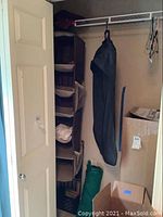 Photo of closet organizer with multiple fabric shelves and mesh pocket, adjacent to a green tent cover and storage boxes.