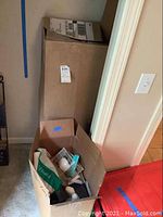 Two cardboard boxes containing various office and personal care items, partially packed.