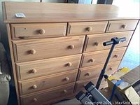 Front view of the pine wood chest of drawers showing all drawers and wooden knobs.