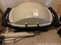 Closed view of Weber portable gas grill showing domed lid and side handles, grill folded compact for storage.