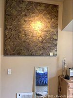 Large square metallic wall art with fleur-de-lis pattern mounted on wall