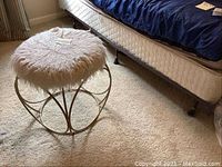 Photo of metal framed stool with white faux fur padded seat on beige carpet