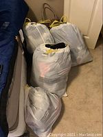 Four large white plastic bags filled with assorted women's clothing and other textile items forming the main lot.