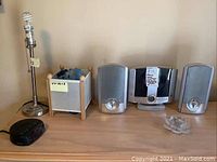 Photo of metallic lamp base, wooden box container, Memorex CD player and two speakers, lotus glass candle holder and black radio clock
