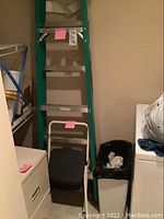 Photo showing 6-foot green fiberglass ladder and two metal step stools stacked in a closet space