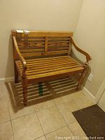 Front view of the wooden bench showing the carved backrest and slatted seat.
