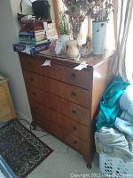 Full view of wooden dresser with drawers and items on top