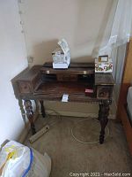 Front view of the vintage wooden writing desk showing its overall shape, drawers, and turned legs.