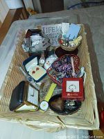 Basket filled with assorted costume jewelry including watches, gift boxes, beads, pins, and frames