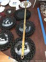 18 pieces of Westmoreland glassware including black glass plates with white painted scenes, white milk glass plates with blue fruit motifs, a milk glass pitcher, candy dish, heart-shaped plates and brass plate hanger