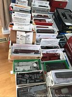 Multiple open model kit boxes and factory assembled cars displayed on table.