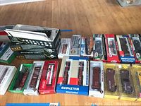 Overall view of FO-scale train cars and kits in original boxes on hardwood floor.