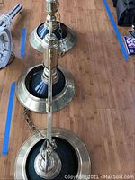 Top view of entire pool table light showing brass finish and green glass shades with suspension chains laid on wooden floor.