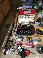 Overall lot showing large cylindrical part, hand tools, wheel balancing kit, brake parts, and assorted small parts in boxes and bags