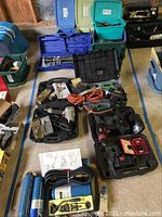 General overview of tools on garage floor including tile cutter, drills, nailer, torch case and miscellaneous items