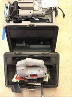 Porter Cable plate joiner and Craftsman Skil jigsaw laid out on floor with their carrying cases.