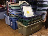 Stacked plastic storage totes in various colors and sizes with lids, showing quantity and condition.