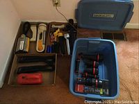 Overview photo of all flashlights arranged on floor and in storage tub under brand label.