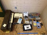 Overview of lot showing electric piano, speakers, cassette players, CD player, manuals and other electronics