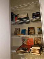 Wire shelves holding multiple dictionaries, thesaurus, poetry volume and small hardbound books.