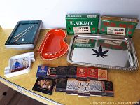 Full lot overview showing all ashtrays, matchbooks, games, and tray arranged on yellow surface.
