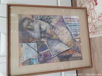 Photo of framed pastel showing reclining nude, abstract geometric background, glass reflection, wall mounted
