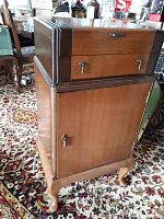 Full view of the antique wooden cabinet showing top drawers and lower cabinet door with ornate legs.