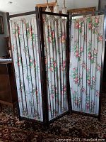 Full view of the three-panel folding screen showing wood frame and floral barkcloth fabric.