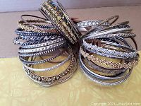 Large assortment of metal bracelets and bangles in silver and gold tones with bead and rhinestone accents