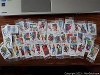 Full spread of 50 sealed mini trading cards displayed on wooden surface below laptop