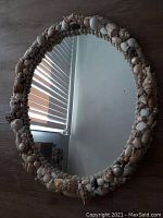 Full view of the oval mirror showing the shell-covered frame and reflective surface.