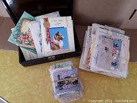 Photo showing two large stacks of bundled cards and a box holding more cards, featuring a card with a dog illustration on top