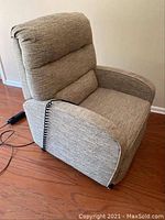 Beige fabric electric lift recliner chair showing wired remote on hardwood floor, angled view
