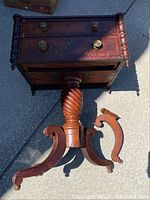 Side view highlighting the detached curved leg against the other three legs and central support column.