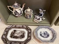 Photo of coffee pot, sugar bowl, creamer, syrup pitcher, large platter, and some plates showing the Mulberry Ironstone collection with scenic transferware in brown and white and intricate detail.