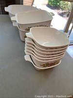 Photo showing two larger white ceramic Corningware casseroles with floral designs, one has a lid