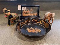 Full lot showing two elephant figurines, tole painted pan, and Asian wood diorama in glass case