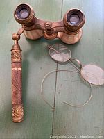 Top view photo of antique opera glasses and wireframe spectacles lying on a green surface
