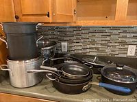 Full set of pots and pans including large stockpot, frying pans, and saucepans with some nested