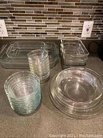 Overview of Pyrex clear glass casseroles, mixing bowls and stackable bowls on kitchen counter.