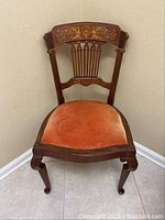 Full front view of antique side chair showing dark coral velvet seat and wooden backrest with marquetry inlay.