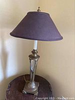 Full view of the decorative table lamp with dark fabric shade, showing overall lamp and cord.