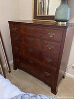 Front view of the antique mahogany chest of drawers showing four drawers with brass handles and the overall finish.