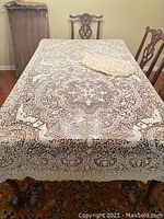 Full view of the lace tablecloth on a dining table with one placemat displayed on top