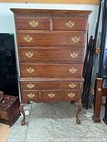 Full view of the tall mahogany highboy chest showing all drawers and carved legs