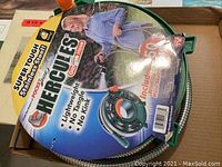Photo showing the front view of the Hercules garden hose packaging and the coiled stainless steel hose on the reel.